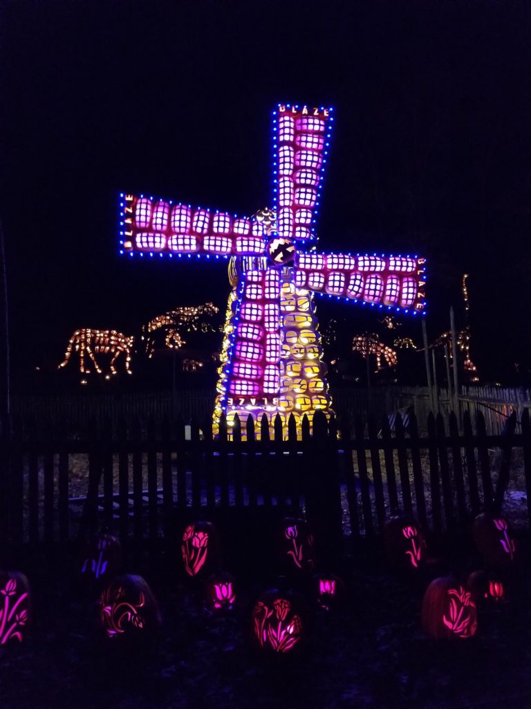 A colorful and illuminated pinwheel made of carved jack o'lantern pumpkins