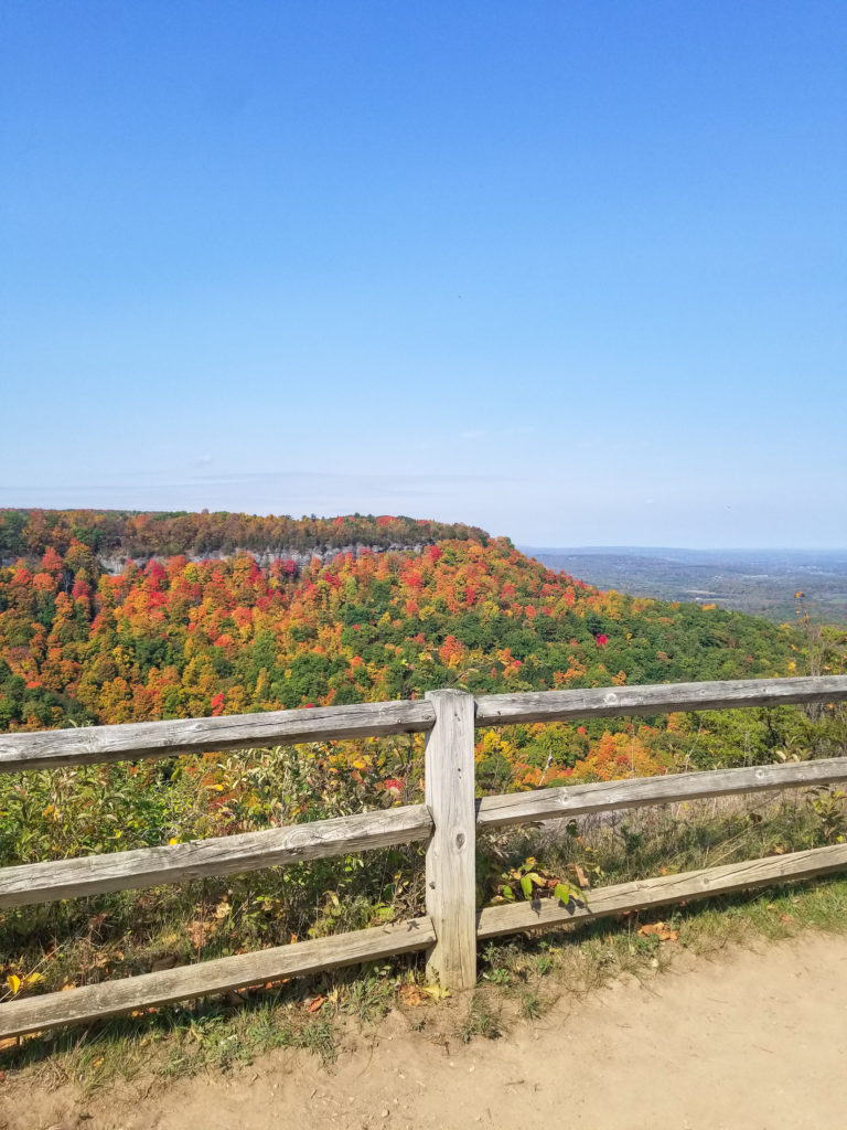 A trail overlooking mountains covered in red, orange, and yellow foliage